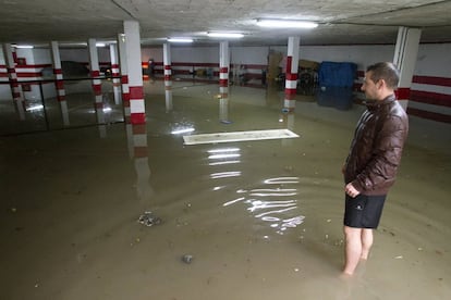 Una persona observa el garaje de su vivienda anegada por las fuertes lluvias en Málaga.