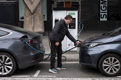 Un hombre carga su coche eléctrico en una calle da Barcelona.