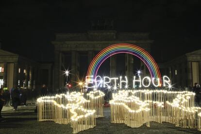 Activistas del Fondo Mundial para la Naturaleza (WWF) escriben las palabras 'Hora de la Tierra' con luces led frente a la puerta de Brandenburgo en Berlín.