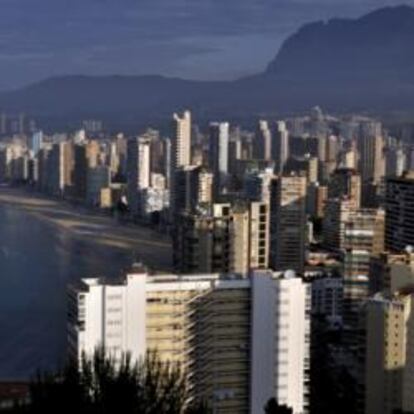 Vista panorámica de Benidorm. Abajo, turistas en la playa de la ciudad alicantina.