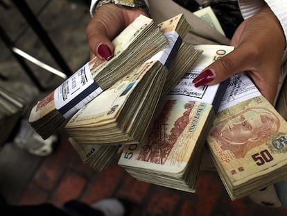 Una mujer sostiene fajos con billetes de soles peruanos, en un centro de cambio en Lima.