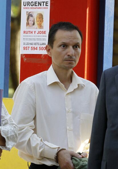 José Bretón, durante la recreación del día en que desaparecieron sus hijos. Tras él, un cartel pide ayuda para encontrar a los menores en la puerta del parque donde el padre asegura que los perdió de vista.