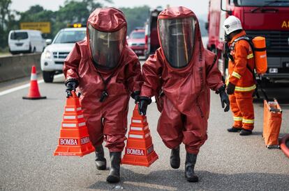 Miembros de un equipo de respuesta a desastres de Malasia con trajes protectores participan en un simulacro en una carretera cerca Bentong, a las afueras de Kuala Lumpur.