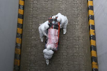 Personal sanitario equipado con trajes de protección trasladan en una camilla de aislamiento a un paciente portador del coronavirus causante de la Covid-19, en Seúl (Corea del Sur).