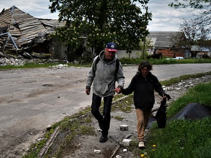 Una pareja camina delante de una vivienda bombardeada en Kupiansk.