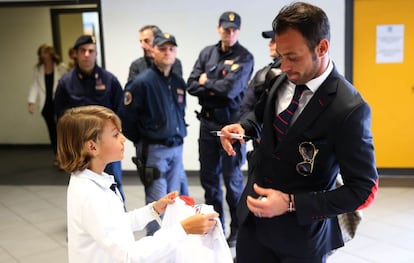 Beto firma un autógrafo a un niño ante la mirada de la policía italiana en el aeropuerto de Turín