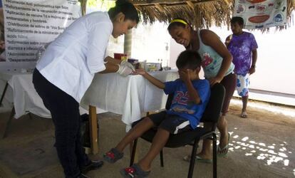 Un niño se tapa los ojos mientras una enfermera le pincha un dedo para hacerle la prueba del chagas.