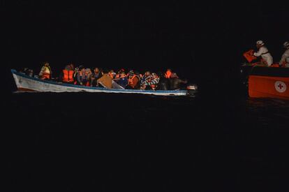 Migrantes se colocan chalecos salvavidas a borde de un bote de madera, cerca de la costa libia. 