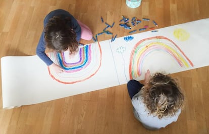 Dos niños pintan dos arcoíris en su casa durante el confinamiento.