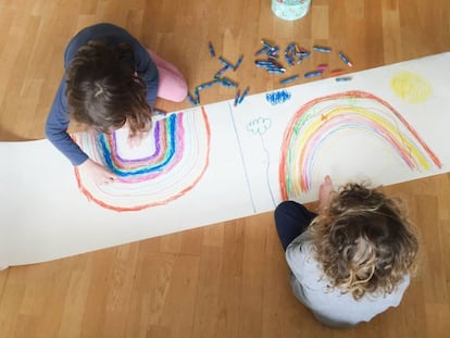 Dos niños pintan dos arcoíris en su casa durante el confinamiento.