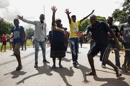 Varias personas alzan las manos mientras bloquean una carretera como protesta por la subida del precio del combustible, en la localidad de Harare.