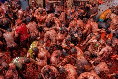 Varias personas cubiertas de tomate participan en la festividad de la Tomatina, este miércoles.