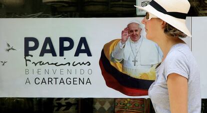 Una mujer camina frente a un cartel con la imagen del papa Francisco en Cartagena (Colombia).