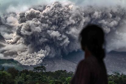 Una mujer observa la erupción del volcán Monte Sinabung desde el pueblo de Tiga Pancur (Indonesia). El volcán entró en erupción en el año 2010 por primera vez en cuatro siglos y, tras otro periodo adormecido, ha permanecido con una gran actividad desde el año 2013. 