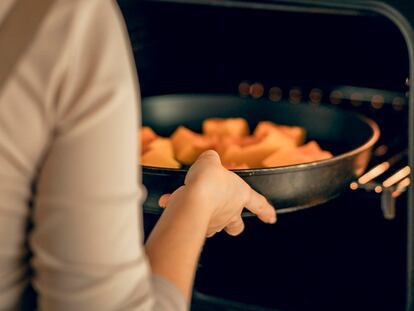 Una persona metiendo la sartén en el horno.