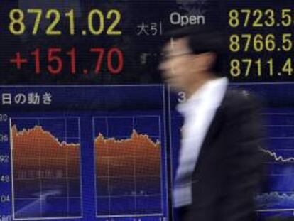 Un ejecutivo japonés camina frente a un tablero electrónico con los resultados de la Bolsa en Tokio, Japón. EFE/Archivo