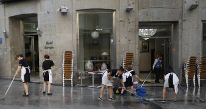 Un grupo de trabajadoras limpia la acera antes de montar la terraza de un hotel madrileño.