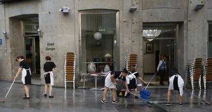 Un grupo de trabajadoras limpia la acera antes de montar la terraza de un hotel madrile&ntilde;o. 