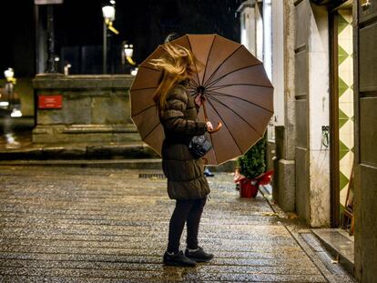 Una chica intenta cerrar el paraguas antes de entrar en un comercio del centro de Girona.