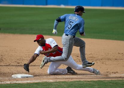 El cubano Alexander Malleta intenta detener al estadounidense Brandon Guyer durante un juego.