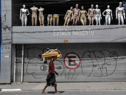 Morador de rua caminha em via comercial esvaziada devido a quarentena no centro de São Paulo.