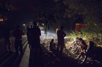 Vecinos de Arbo descansan durante los trabajos para controlar el avance del mayor incendio del verano, esta madrugada.