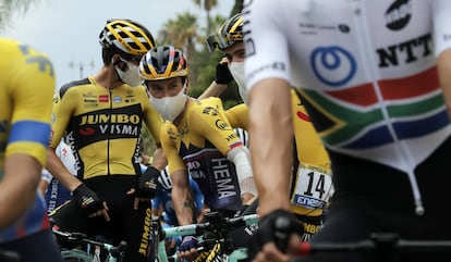 El ciclista esloveno Primoz Roglic de Eslovenia (en el centro) utiliza mascarilla antes del inicio de la carrera.