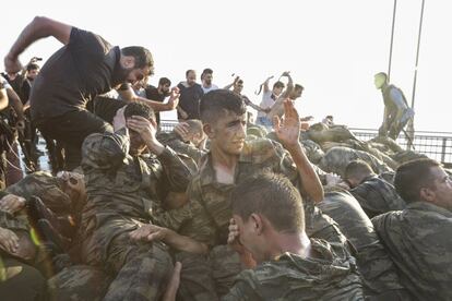 Militares turcos montam guarda em na praça de Taksim em Istambul enquanto várias pessoas erguem a bandeira turca, em 17 de julho de 2016. O golpe de Estado na Turquia fracassa depois da resistência da população nas ruas.