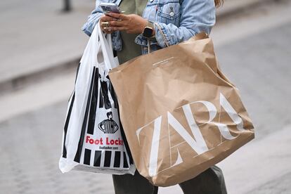 Una mujer pasea por la calle tras hacer unas compras.