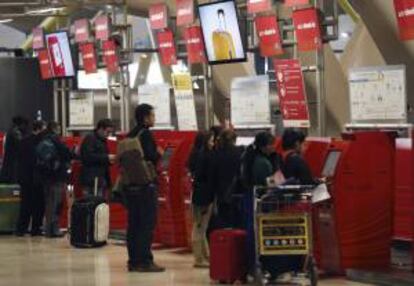 Varias personas guardan cola junto a los mostradores de facturación de la Terminal T4 del aeropuerto de Madrid-Barajas. EFE/Archivo