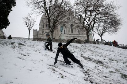 Dos jóvenes se deslizan con sus tablas de 'snowboard' frente a la basílica del Sagrado Corazón en Montmarte.
