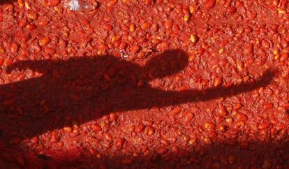 Sombra de una persona proyectada sobre tomates en la calle principal de Buñol.