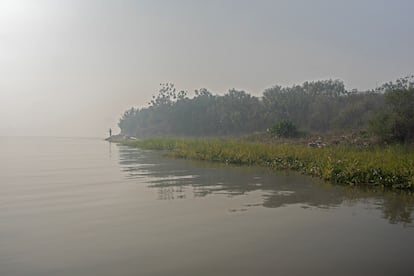 Un pescador en las costas del río, bajo una nube de humo. 