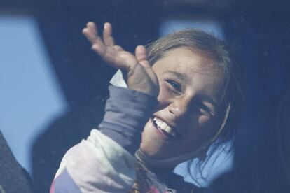 Una niña iraquí saluda desde el autobús en el que abandona con su familia el campo de refugiados de Idomeni, desde donde se dirigen a otro campamento en la ciudad griega de Katerini.