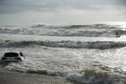 Surfistes aprofiten les onades mentre un cotxe ha quedat engolit per la mar.