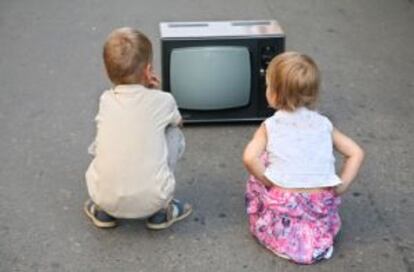 Dos ni&ntilde;os frente a un televisor.