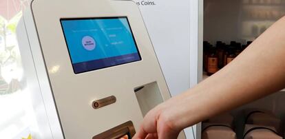 Un cliente introduce un billete en una máquina Bitcóin para comprar criptomoneda.