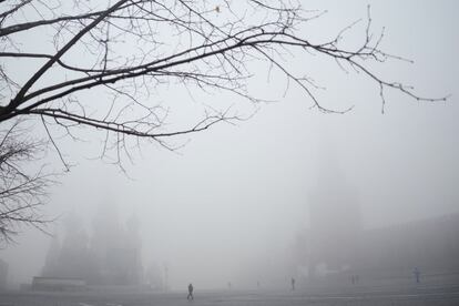 La gente camina en la Plaza Roja, con la Torre Spasskaya, a la derecha, y la Catedral de San Basilio visibles a través de la niebla en Moscú. Una densa niebla envolvió la capital rusa este martes, causando numerosos retrasos en los vuelos en los aeropuertos de la capital rusa.