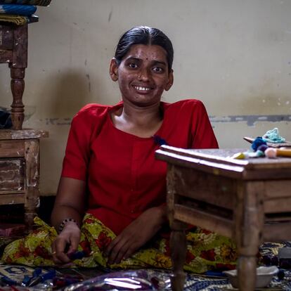 Lakshmi tenía cuatro años cuando le diagnosticaron polio, una enfermedad de la que no había sido vacunada. Desde entonces sufre un 90% de discapacidad y unas secuelas que la obligan a desplazarse a gatas, arrastrando sus inertes piernas. Cuando sus padres conocieron la fatal noticia sobre la salud de su única hija, reaccionaron de distinta manera. La apoyaron su madre y su abuela, quienes la ayudaron y enseñaron a ducharse, a vestirse sola y hasta a cocinar. Su padre, sin embargo, no se tomó su discapacidad igual de bien, y acostumbraba a golpearla y despreciarla hasta que hace cinco años abandonó el hogar conyugal. Pese a sus dificultades para desplazarse, Lakshmi decidió que quería estudiar y llegó hasta el séptimo grado en la escuela de su pueblo. Hasta ella llegaba arrastrándose por el suelo con ayuda de sus delgados brazos. Cuando aprobó el último año tiró la toalla porque en su colegio no había más cursos y, para seguir, hubiera tenido que ir a otro pueblo, algo que le era imposible. Desde entonces, lo único que hacía cada día era quedarse en casa y, como mucho, ir a la de una vecina a ver la televisión. Hace tres años su aburrida rutina cambió, pues empezó trabajar en la Fundación Vicente Ferrer, donde se ha hecho experta en joyería y en yute, un material parecido al cáñamo con el que ella y sus compañeras fabrican artículos de decoración. Hoy mantiene a su madre, que tuvo que dejar de trabajar en el campo por problemas de salud, y no se rinde ante nada.