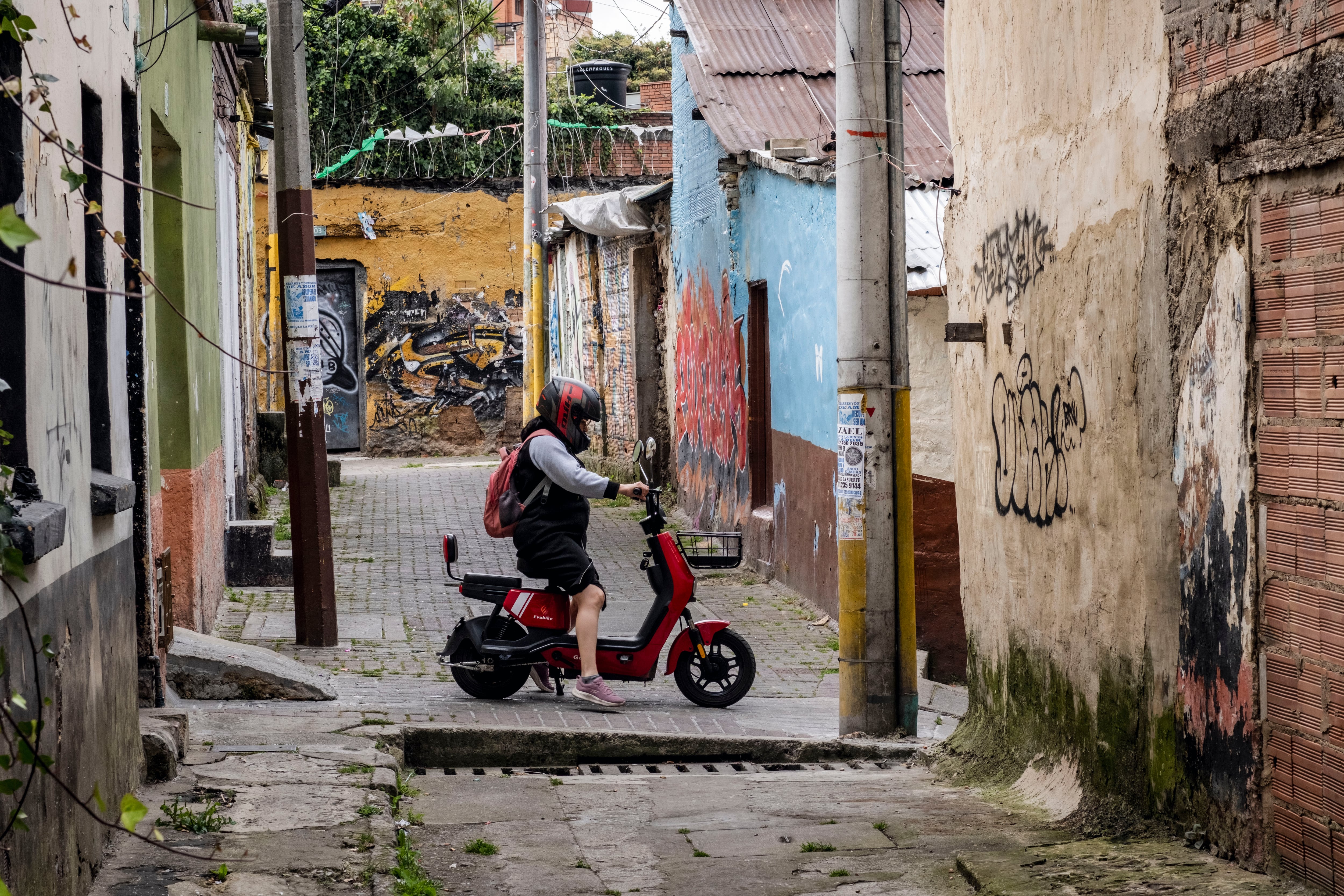 Una mujer sale de su casa en una scooter eléctrica, en el barrio San Martín.