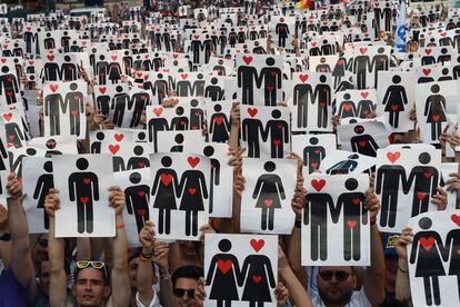 Cientos de personas sostienen pancartas con corazones y parejas, durante un flash mob durante el desfile del orgullo en Milán.