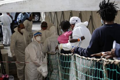 A su salida del 'Sea Watch 3', los migrantes reciben la ayuda de miembros de la Cruz Roja y sanitarios italianos para desembarcar en el puerto siciliano de Pozzallo, Italia, el 23 de octubre de 2021. Esta vez, la misión del Sea Watch ha tenido éxito.