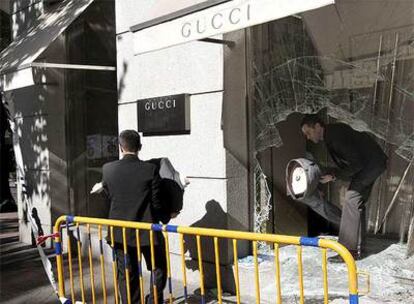 Dos dependientes retiran los maniquíes tras la luna reventada, esta mañana en la tienda de Gucci.