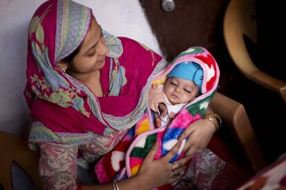 Una madre sostiene a su bebé en Agra (India). 