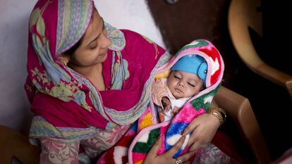 Una madre sostiene a su bebé en Agra (India). 