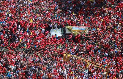 Caracas, Venezuela, 6 de marzo de 2013. Una multitud rodea el coche fúnebre del presidente de Venezuela Hugo Chavez por las calles de Caracas durante su traslado desde el hospital en el que murió hasta la academia militar. Chavez falleció en Caracas a las 16.25 horas (21.55 hora peninsular española), según anunció oficialmente el vicepresidente Nicolás Maduro. Maduro dio la información rodeado de ministros del gabinete desde el vestíbulo del Hospital Militar de Caracas, donde se hallaba ingresado el presidente desde el 18 de febrero. La Constitución prevé que al morir el mandatario asuma su lugar el presidente del Parlamento, Diosdado Cabello, quien debe convocar elecciones en el plazo de un mes. En cambio, el ministro de Exteriores, Elías Jaua, anunció que iba a ser el vicepresidente Nicolás Maduro el que tomaría posesión del cargo como presidente interino.