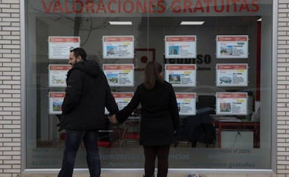 Dos personas miran el escaparate de una inmobiliaria en Madrid.