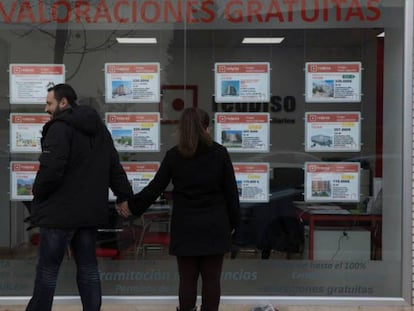 Dos personas miran el escaparate de una inmobiliaria en Madrid.