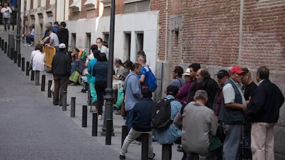 Un grupo de personas hace cola para entrar en un comedor social en Madrid