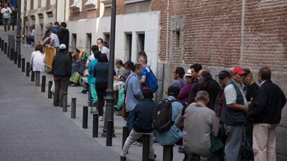 Un grupo de personas hace cola para entrar en un comedor social en Madrid